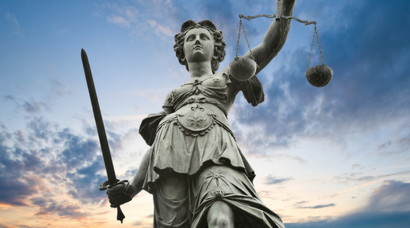 a statue that represents justice holds scales and a sword