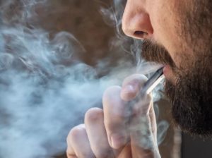 E-Cigarette Explosion Injury Lawsuit. Man with beard smoking an e-cigarette.