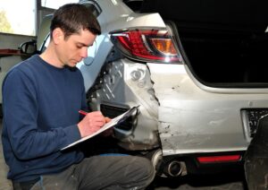 An insurance specialist inspects the vehicle following an accident. 