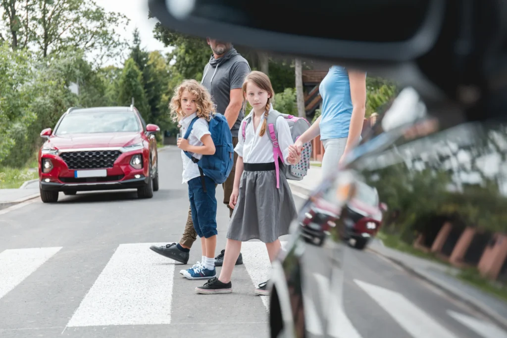 Children crossing a street at a crosswalk in Columbia, TN with approaching vehicles.