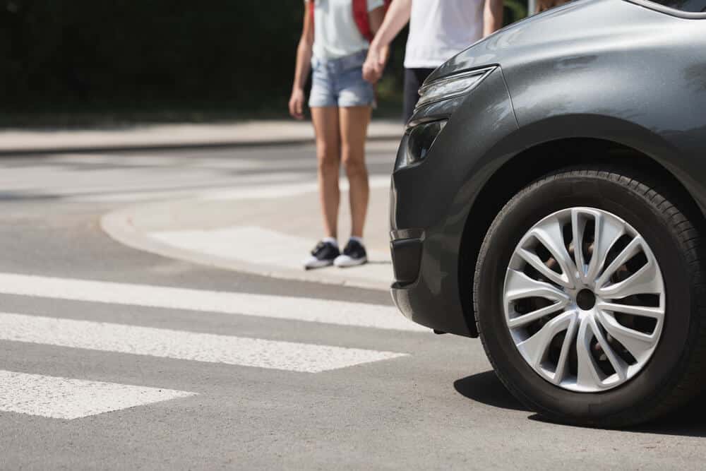 Pedestrians waiting to cross the street as a vehicle approaches a crosswalk in Gallatin, Tennessee.