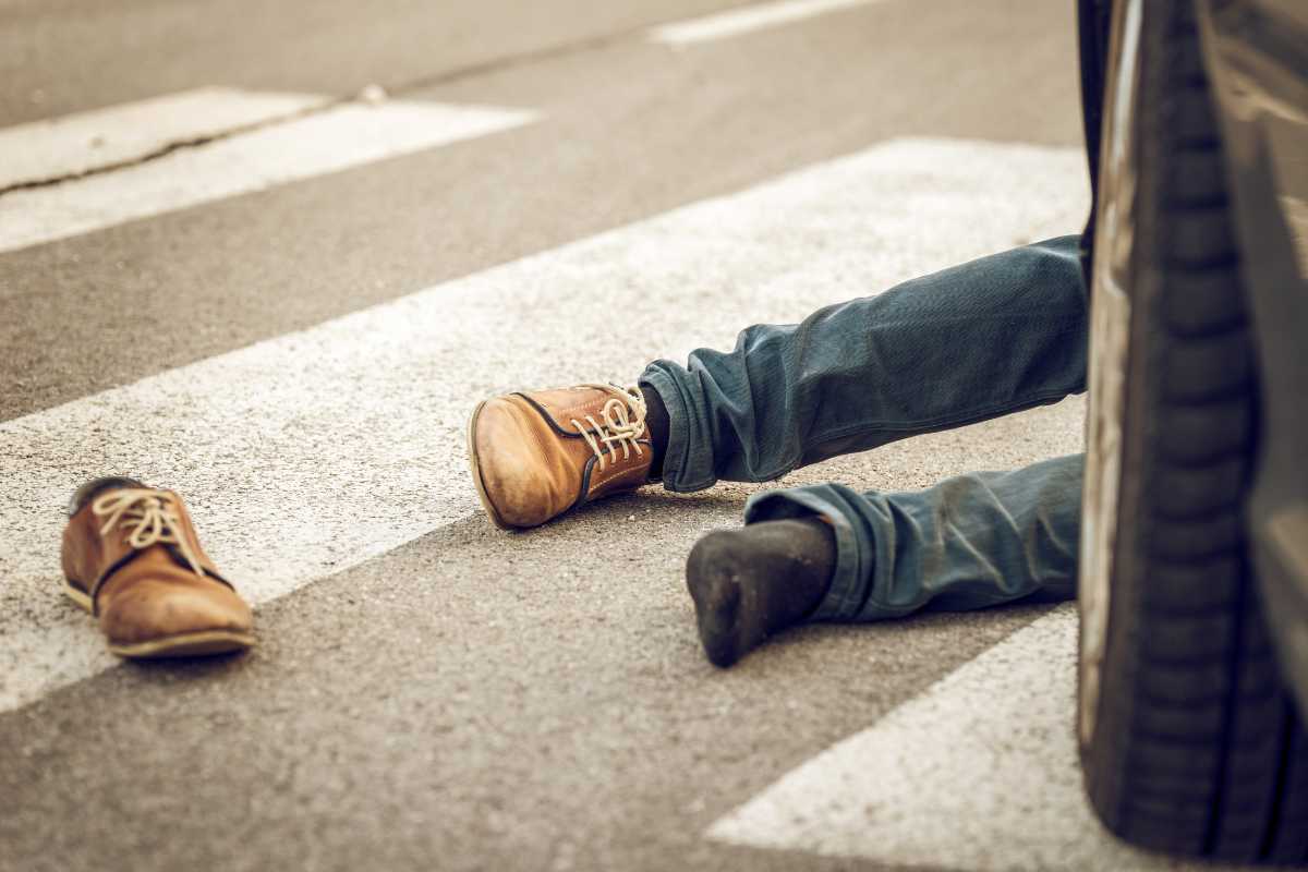Victim lying in a crosswalk next to a car tire after an Alabama pedestrian accident.