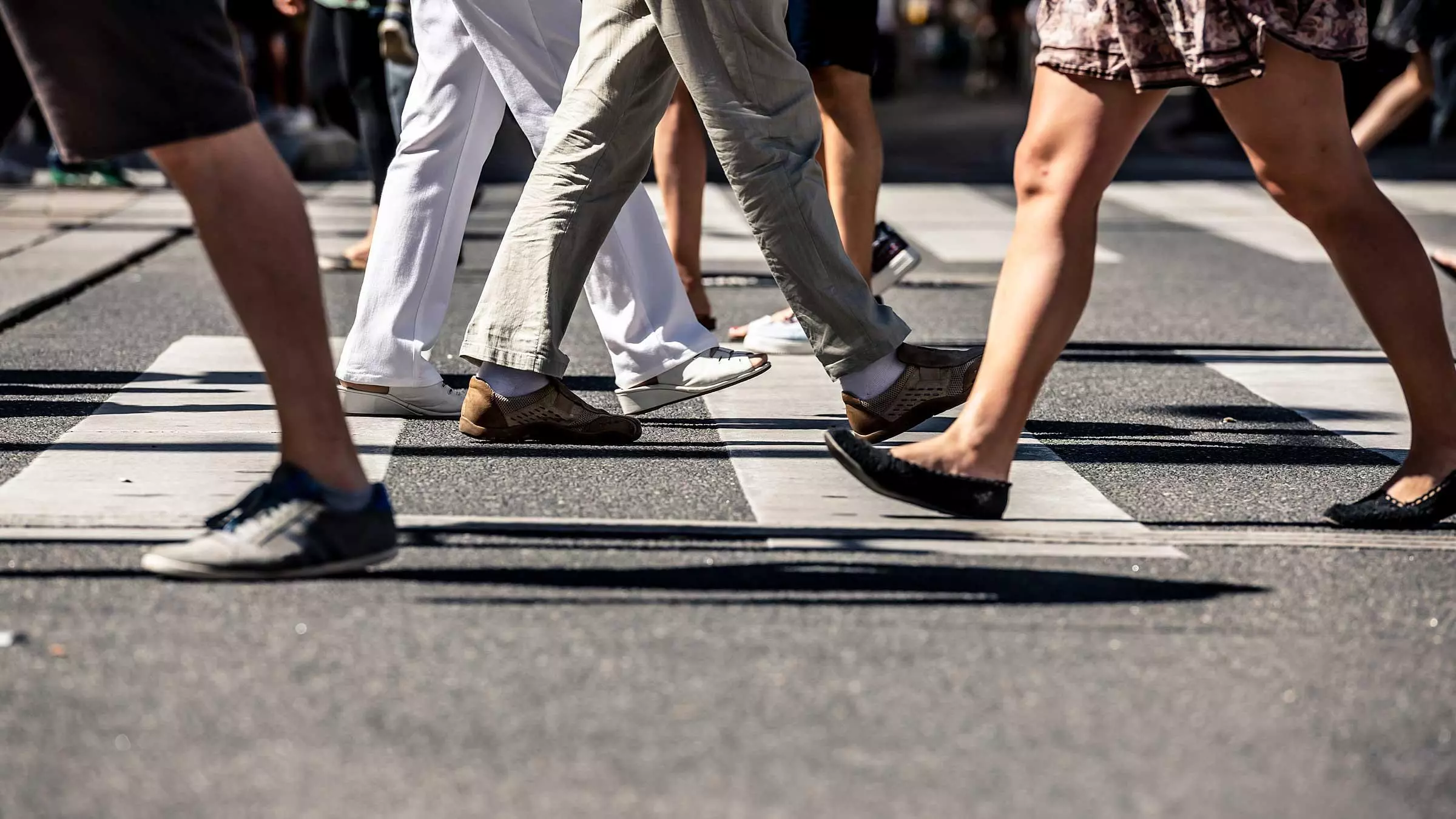 Close-up of pedestrians walking across a marked crosswalk in a busy area where an Alabama pedestrian accident could happen.