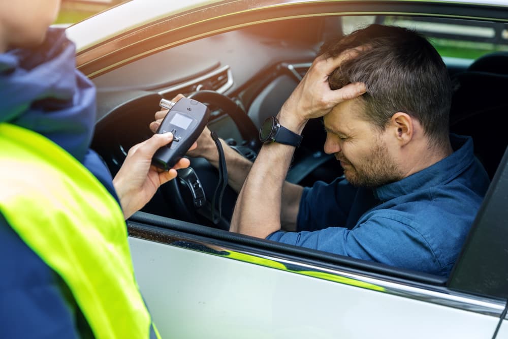 Police officer gives a breathalyzer test to a distressed driver, illustrating a Birmingham drunk driving accident case
