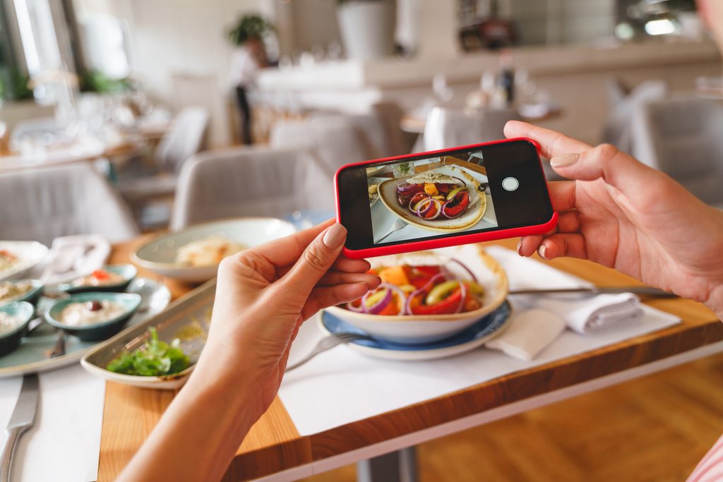 Diner photographing a restaurant meal with a smartphone to document the food