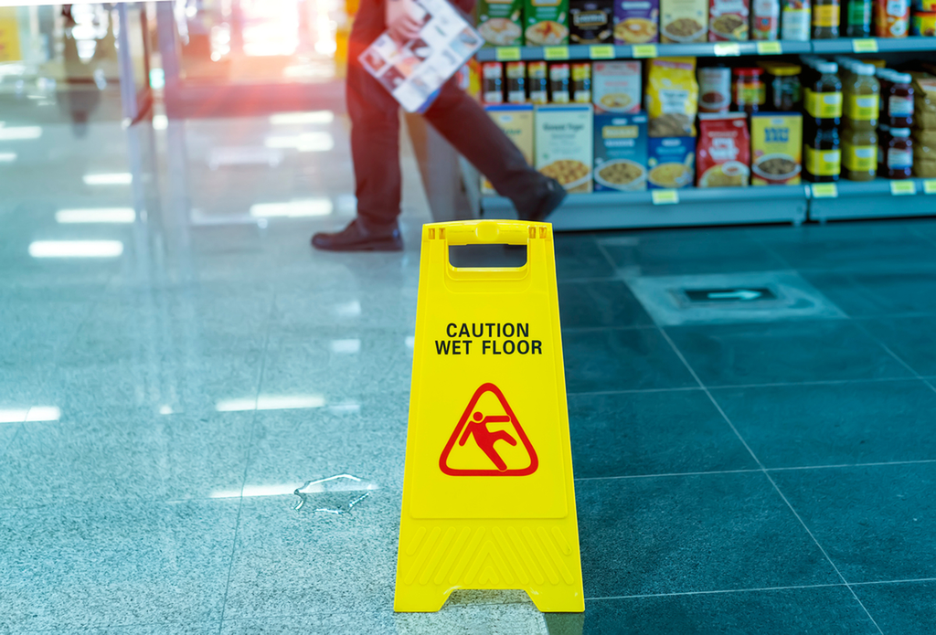 Wet floor caution sign next to a spill in a grocery store aisle, a common cause of slip and fall injuries in Alabama